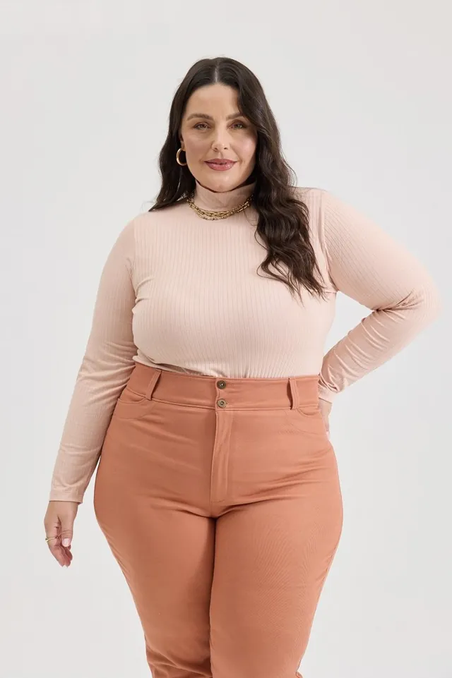 Plus size model wearing terracotta skinny pants and a light top
