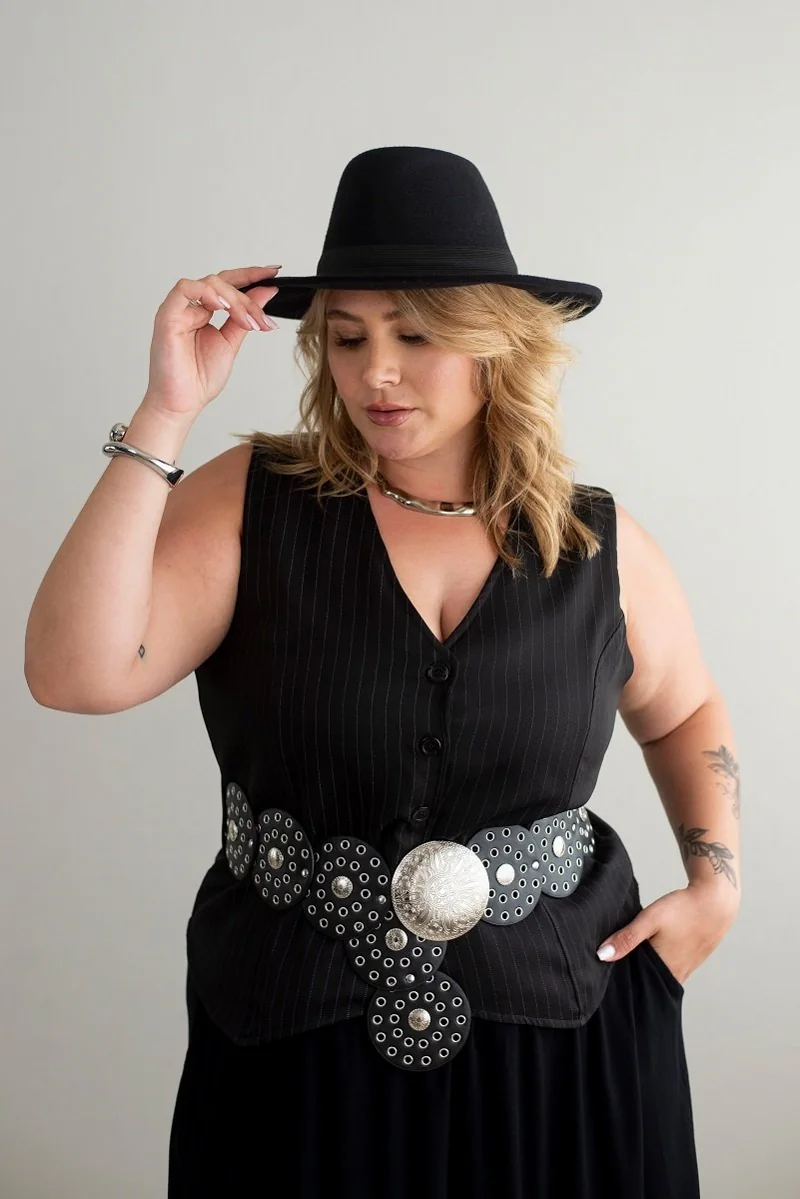 Plus size model wearing a pinstripe vest, belt and hat